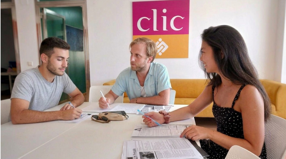 Estudiantes en una clase de español trabajando en grupo con materiales de aula